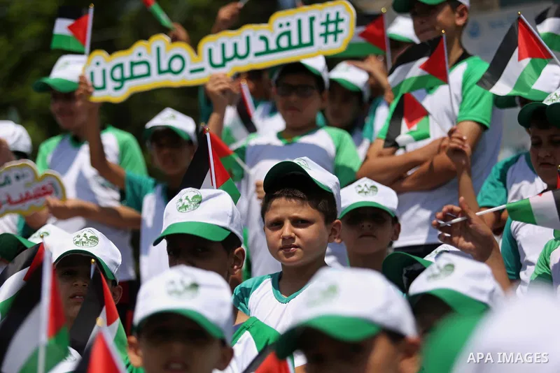 Palestinian children hold the national flags during the announcement the start of summer camps organized by the Hamas movement in Gaza city on July 8, 2017. Photo by Ashraf Amra