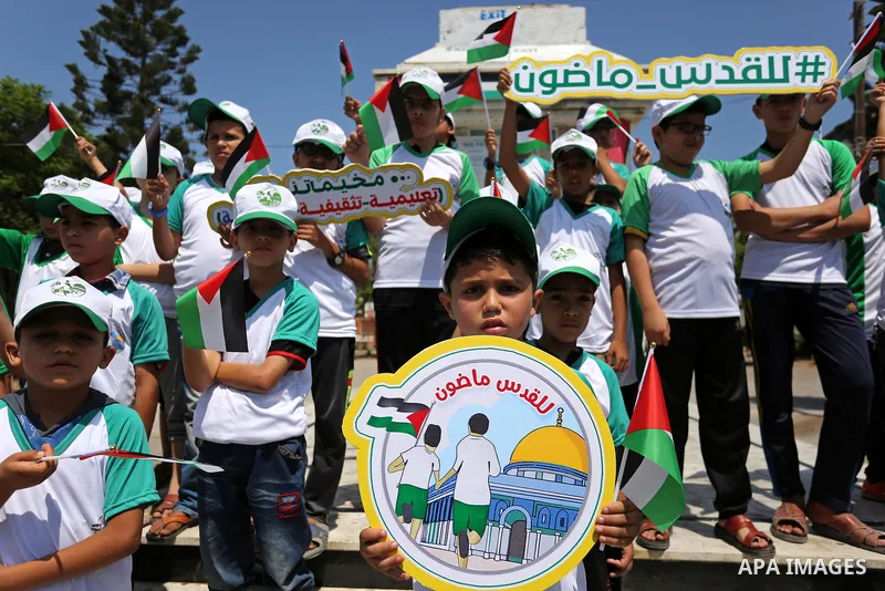 Palestinian children hold the national flags during the announcement the start of summer camps organized by the Hamas movement in Gaza city on July 8, 2017. Photo by Ashraf Amra