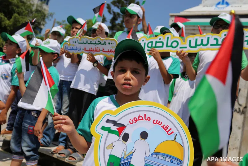 Palestinian children hold the national flags during the announcement the start of summer camps organized by the Hamas movement in Gaza city on July 8, 2017. Photo by Ashraf Amra