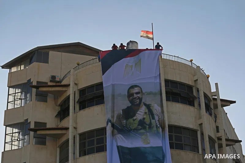 Palestinian men hang a large banner depicting portraits of the Egyptian soldiers, who were killed a day earlier in the restive Sinai Peninsula in an attack by the Islamic State (IS) group, during a funeral service in Gaz...