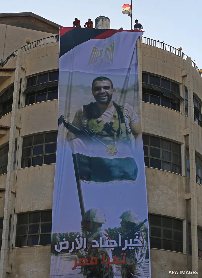 Palestinian men hang a large banner depicting portraits of the Egyptian soldiers, who were killed a day earlier in the restive Sinai Peninsula in an attack by the Islamic State (IS) group, during a funeral service in Gaz...