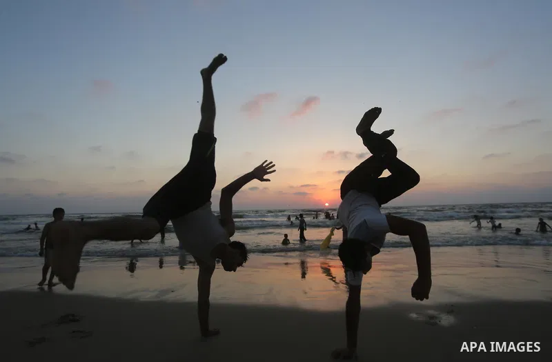 Palestinian youths play gymnastics on the coast of Gaza city during sunset on July 8, 2017. Photo by Mohammed Asad
