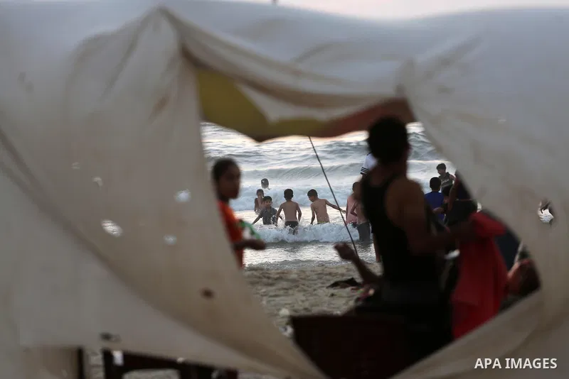 Palestinians swim in the Mediterranean sea on the coast of Gaza city during sunset on July 8, 2017. Photo by Mohammed Asad