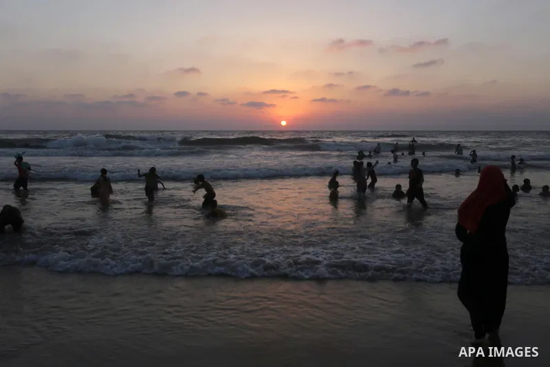 Palestinians swim in the Mediterranean sea on the coast of Gaza city during sunset on July 8, 2017. Photo by Mohammed Asad