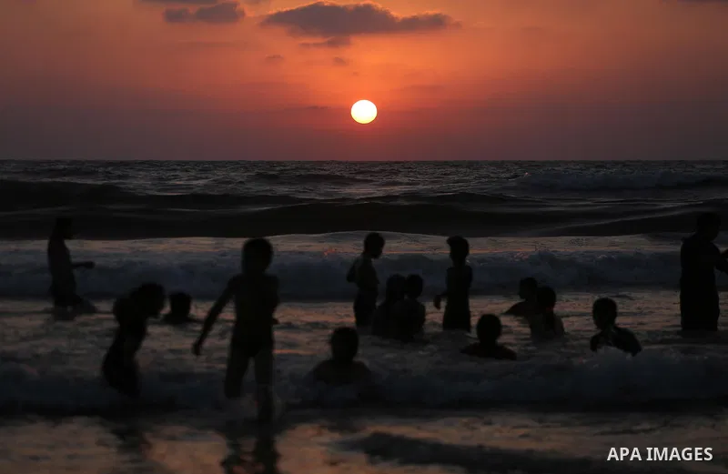 Palestinians swim in the Mediterranean sea on the coast of Gaza city during sunset on July 8, 2017. Photo by Mohammed Asad