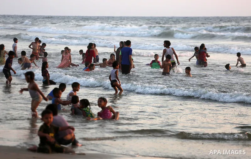 Palestinians swim in the Mediterranean sea on the coast of Gaza city during sunset on July 8, 2017. Photo by Mohammed Asad