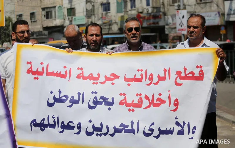 Palestinian released prisoners from Israeli jails hold placards during a protest demanding their salaries in Gaza city on July 9, 2017. Photo by Mohammed Asad