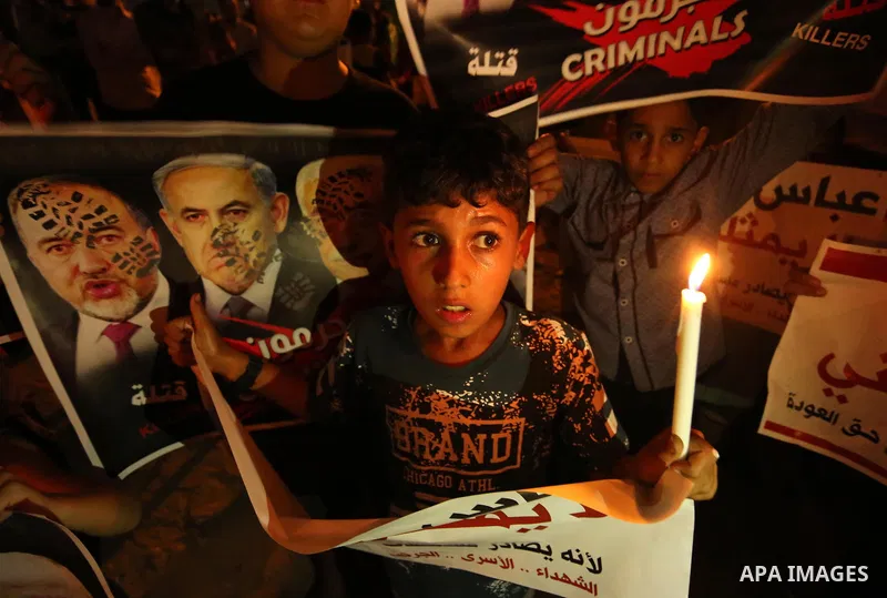 Palestinian boys hold candles and posters during a protest against the blockade on Gaza, in Khan Younis in the southern Gaza Strip July 14, 2017. The poster (back) reads, "Abbas (Palestinian president) does not represent...