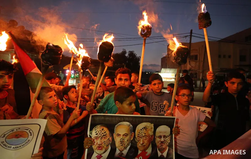 Palestinian boys hold candles and posters during a protest against the blockade on Gaza, in Khan Younis in the southern Gaza Strip July 14, 2017. The poster (back) reads, "Abbas (Palestinian president) does not represent...