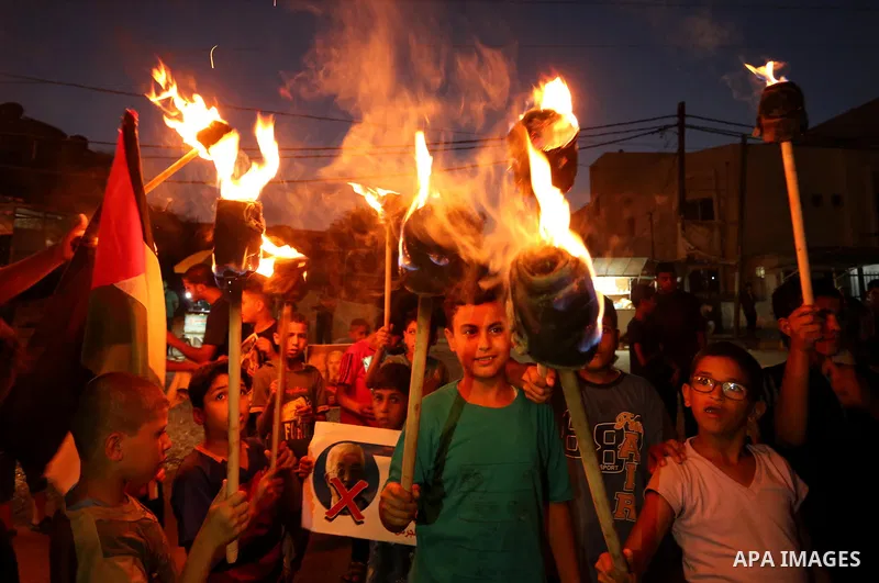 Palestinian boys hold candles and posters during a protest against the blockade on Gaza, in Khan Younis in the southern Gaza Strip July 14, 2017. The poster (back) reads, "Abbas (Palestinian president) does not represent...