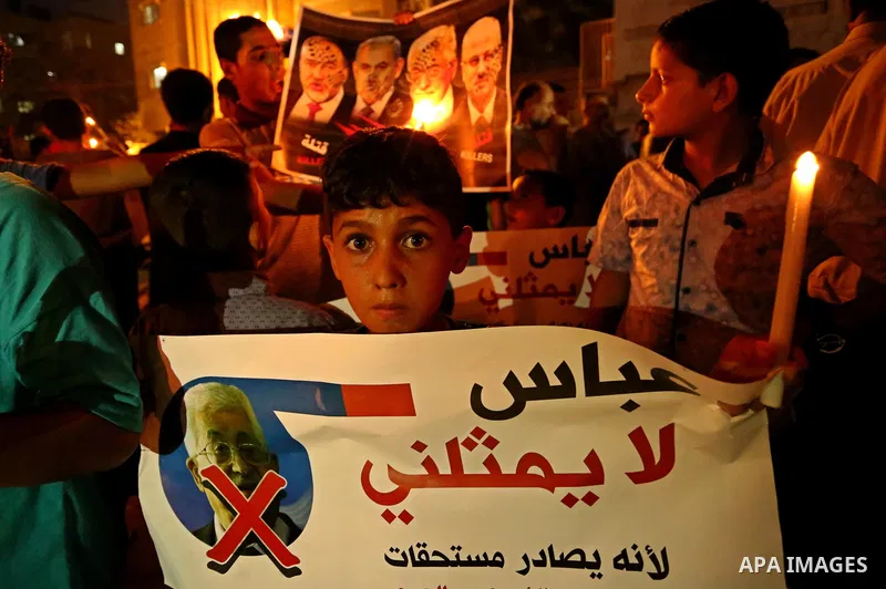 Palestinian boys hold candles during a protest against the blockade on Gaza, in Khan Younis in the southern Gaza Strip July 14, 2017. The poster (back) reads, "Abbas (Palestinian president) does not represent me because...