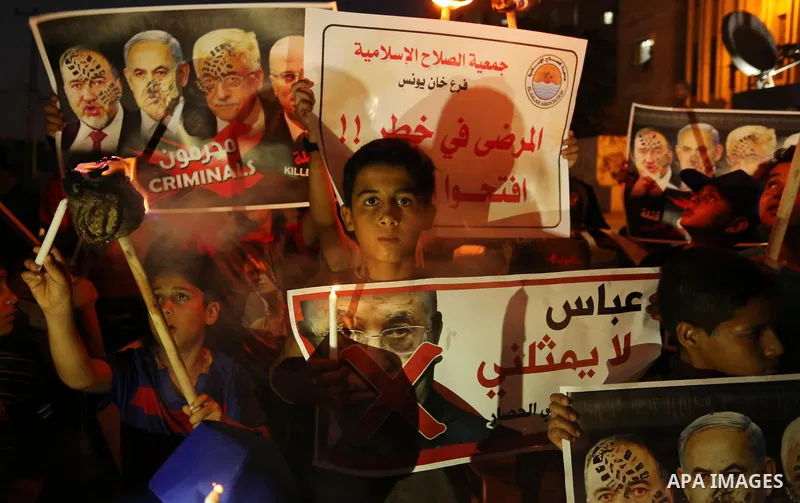 Palestinian boys hold candles and posters during a protest against the blockade on Gaza, in Khan Younis in the southern Gaza Strip July 14, 2017. The poster (back) reads, "Abbas (Palestinian president) does not represent...