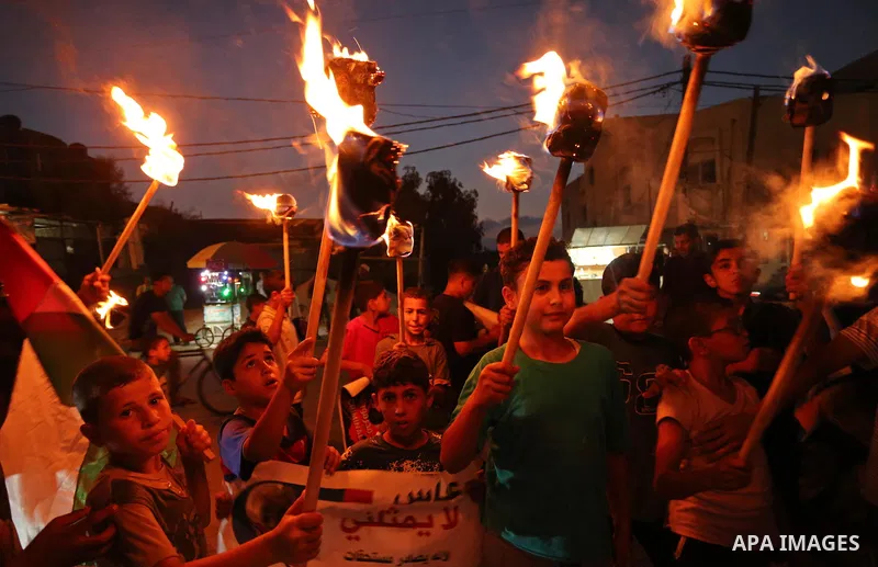 Palestinian boys hold candles and posters during a protest against the blockade on Gaza, in Khan Younis in the southern Gaza Strip July 14, 2017. The poster (back) reads, "Abbas (Palestinian president) does not represent...