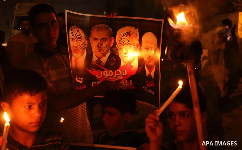 Palestinian boys hold candles and posters during a protest against the blockade on Gaza, in Khan Younis in the southern Gaza Strip July 14, 2017. The poster (back) reads, "Abbas (Palestinian president) does not represent...