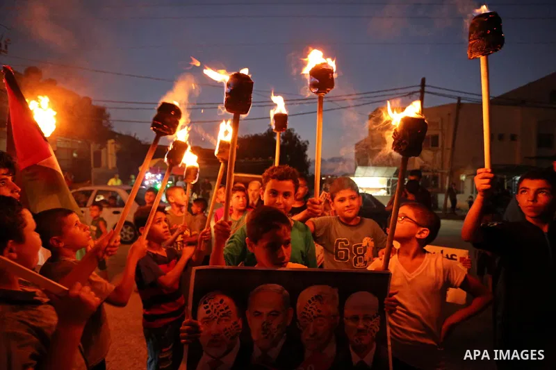 Palestinian boys hold candles and posters during a protest against the blockade on Gaza, in Khan Younis in the southern Gaza Strip July 14, 2017. The poster (back) reads, "Abbas (Palestinian president) does not represent...