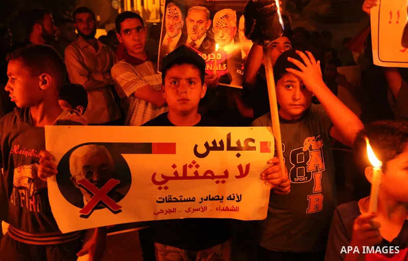 Palestinian boys hold candles during a protest against the blockade on Gaza, in Khan Younis in the southern Gaza Strip July 14, 2017. The poster (back) reads, "Abbas (Palestinian president) does not represent me because...
