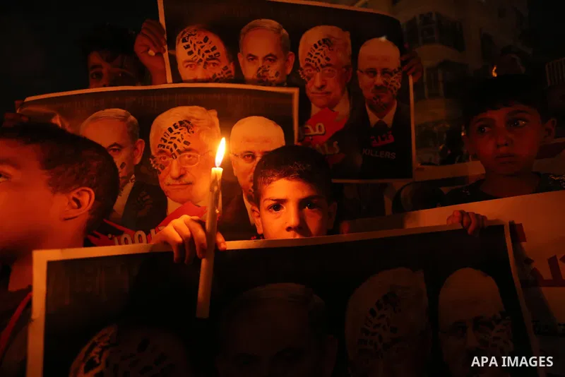 Palestinian boys hold candles and posters during a protest against the blockade on Gaza, in Khan Younis in the southern Gaza Strip July 14, 2017. The poster (back) reads, "Abbas (Palestinian president) does not represent...