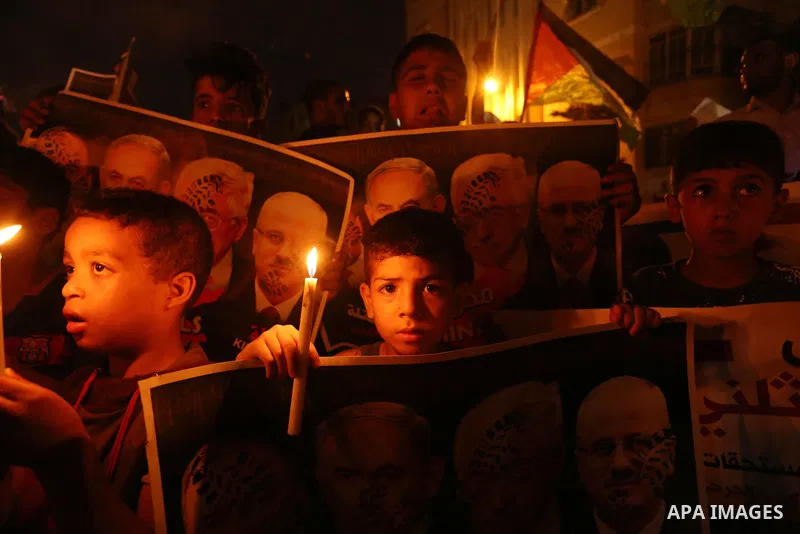 Palestinian boys hold candles and posters during a protest against the blockade on Gaza, in Khan Younis in the southern Gaza Strip July 14, 2017. The poster (back) reads, "Abbas (Palestinian president) does not represent...