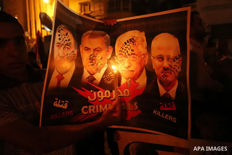 Palestinian boys hold candles and posters during a protest against the blockade on Gaza, in Khan Younis in the southern Gaza Strip July 14, 2017. The poster (back) reads, "Abbas (Palestinian president) does not represent...