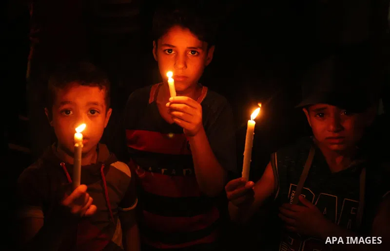 Palestinian boys hold candles and posters during a protest against the blockade on Gaza, in Khan Younis in the southern Gaza Strip July 14, 2017. Photo by Ashraf Amra