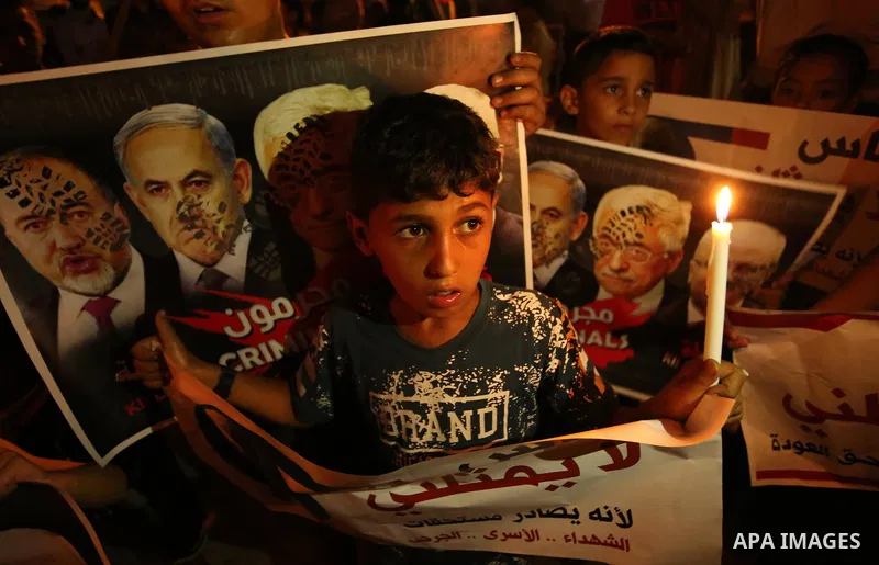 A Palestinian boy holds a candle during a protest against the blockade on Gaza, in Khan Younis in the southern Gaza Strip July 14, 2017. The poster (back) reads, "Abbas (Palestinian president) does not represent me becau...