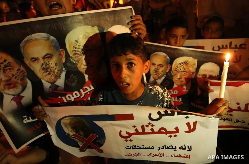 A Palestinian boy holds a candle during a protest against the blockade on Gaza, in Khan Younis in the southern Gaza Strip July 14, 2017. The poster (back) reads, "Abbas (Palestinian president) does not represent me becau...