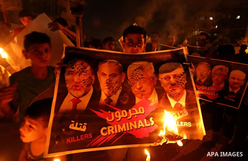 Palestinians burn a poster depicting Palestinian President Mahmoud Abbas, Israeli Prime Minister Benjamin Netanyahu and Israeli Defence Minister Avigdor Lieberman as they step on it during a protest against the blockade...