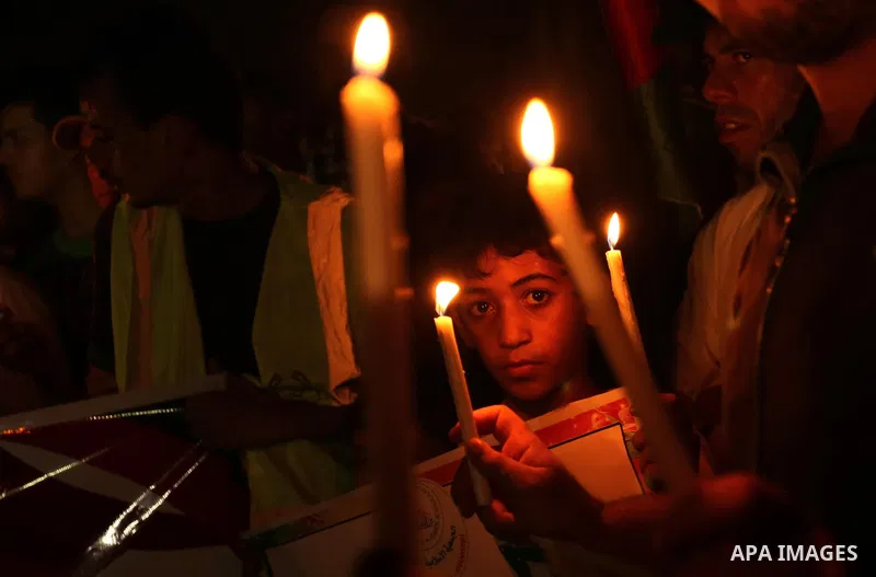 Palestinian boys hold candles and posters during a protest against the blockade on Gaza, in Khan Younis in the southern Gaza Strip July 14, 2017. Photo by Ashraf Amra