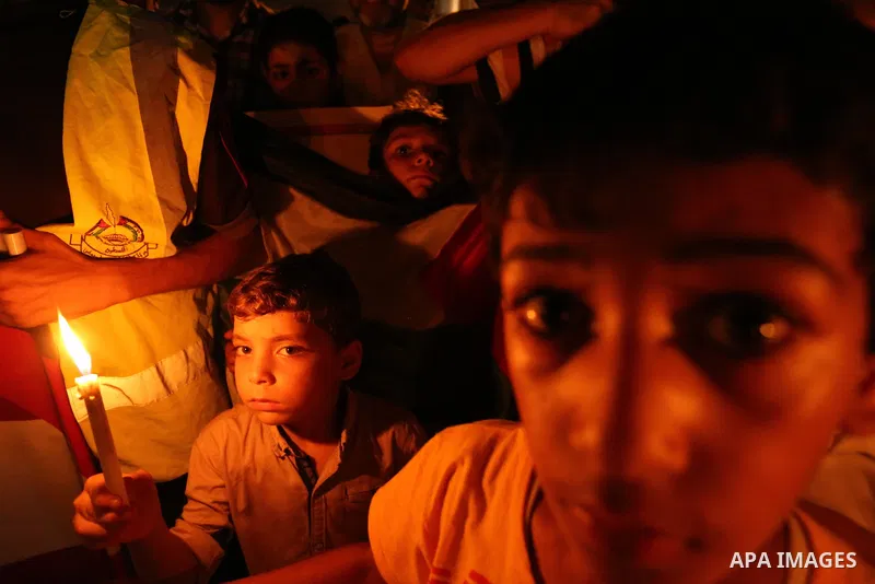 Palestinian boys hold candles and posters during a protest against the blockade on Gaza, in Khan Younis in the southern Gaza Strip July 14, 2017. Photo by Ashraf Amra