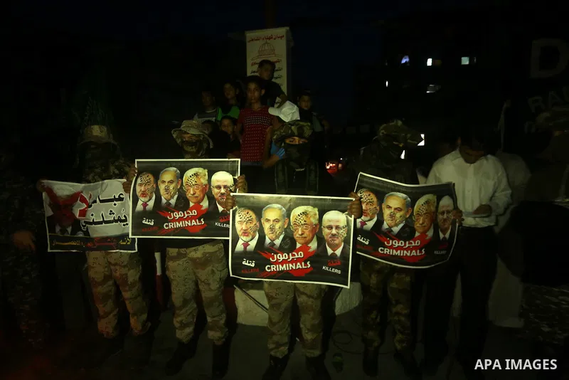 Members the Ezzedine al-Qassam Brigades, the military wing of the Palestinian Islamist movement Hamas hold poster depicting Israeli Defence Minister Avigdor Lieberman, Israeli Prime Minister Benjamin Netanyahu, Palestini...
