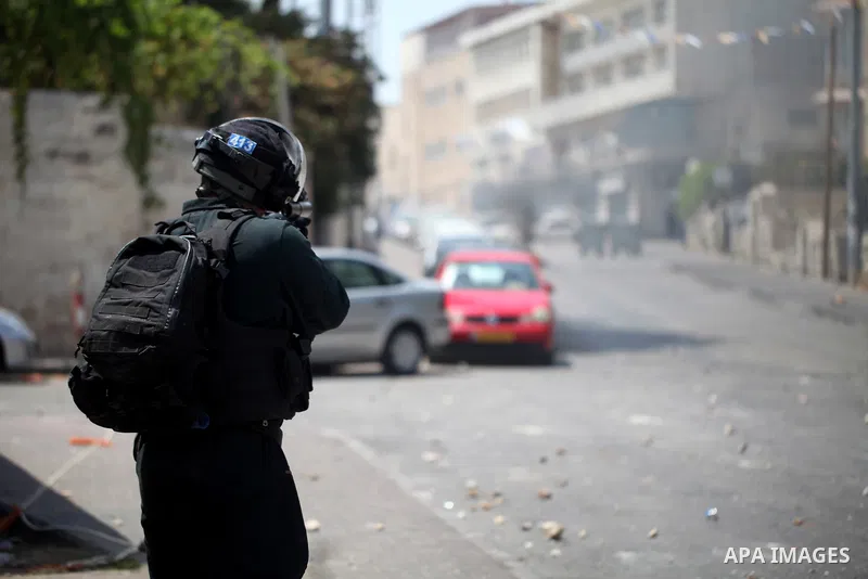 A member of Israeli security forces aims his weapon towards Palestinian protesters during clashes following Friday prayer outside Jerusalem's Old City on July 21, 2017, after Israeli police barred men under 50 from enter...