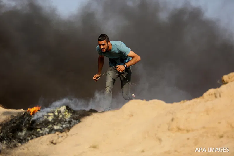 A Palestinian protester uses a slingshot to hurl stones towards Israeli security forces during clashes near the border between Israel and central Gaza Strip in a protest against Israel's new security measures at the entr...