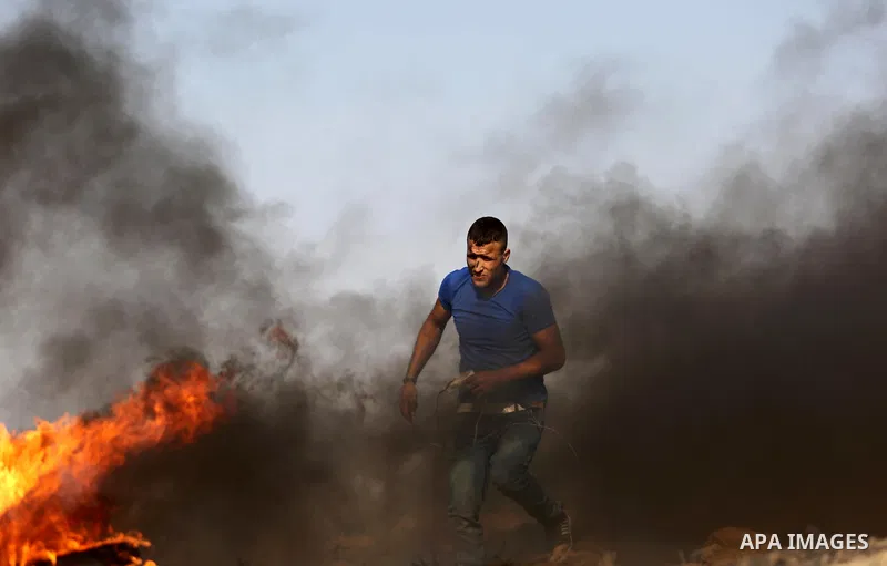 A Palestinian protester uses a slingshot to hurl stones towards Israeli security forces during clashes near the border between Israel and central Gaza Strip in a protest against Israel's new security measures at the entr...