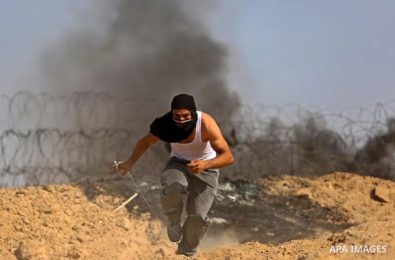 A Palestinian protester uses a slingshot to hurl stones towards Israeli security forces during clashes near the border between Israel and central Gaza Strip in a protest against Israel's new security measures at the entr...
