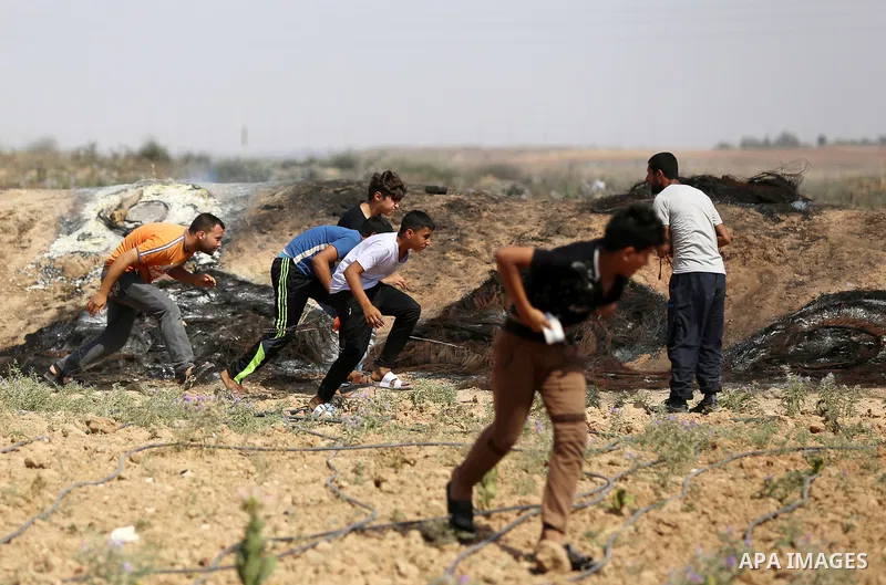 Palestinian protesters take cover during clashes with Israeli security forces near the border fence east of Jabalia refugee camp in a protest against Israel's new security measures at the entrance to the al-Aqsa mosque c...