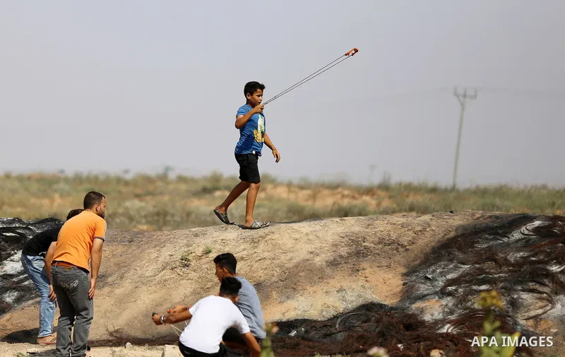 A Palestinian protester uses a slingshot to hurl stones towards Israeli security forces during clashes near the border fence east of Jabalia refugee camp in a protest against Israel's new security measures at the entranc...