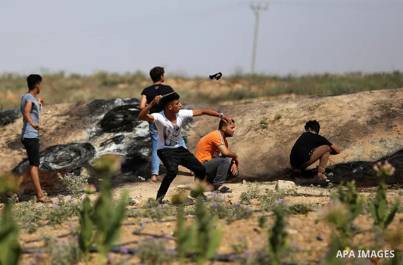 A Palestinian protester uses a slingshot to hurl stones towards Israeli security forces during clashes near the border fence east of Jabalia refugee camp in a protest against Israel's new security measures at the entranc...