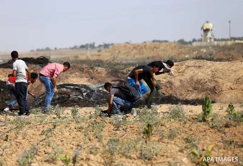 Palestinian protesters take cover during clashes with Israeli security forces near the border fence east of Jabalia refugee camp in a protest against Israel's new security measures at the entrance to the al-Aqsa mosque c...