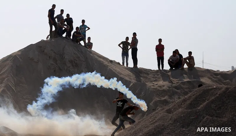 A Palestinian protester throws back a teargas canister fired by Israeli security forces during clashes near the border between Israel and eastern Gaza strip in a protest against Israel's new security measures at the entr...