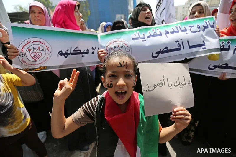 Palestinian protesters shout slogans and hold placards during a demonstration against Israeli security measures that were implemented at the Al-Aqsa mosque compound in Jerusalem the previous week prior to being removed a...