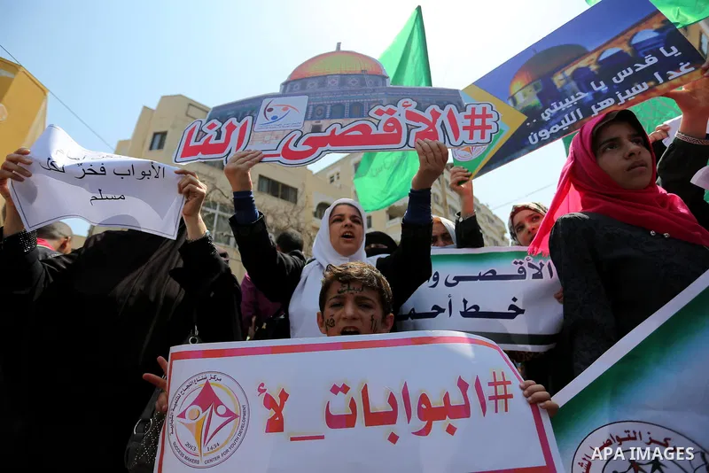 Palestinian protesters shout slogans and hold placards during a demonstration against Israeli security measures that were implemented at the Al-Aqsa mosque compound in Jerusalem the previous week prior to being removed a...