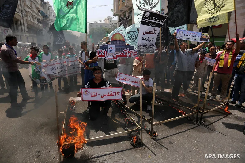 Palestinian protesters burn models of metal detectors during a demonstration against Israeli security measures that were implemented at the Al-Aqsa mosque compound in Jerusalem the previous week prior to being removed af...