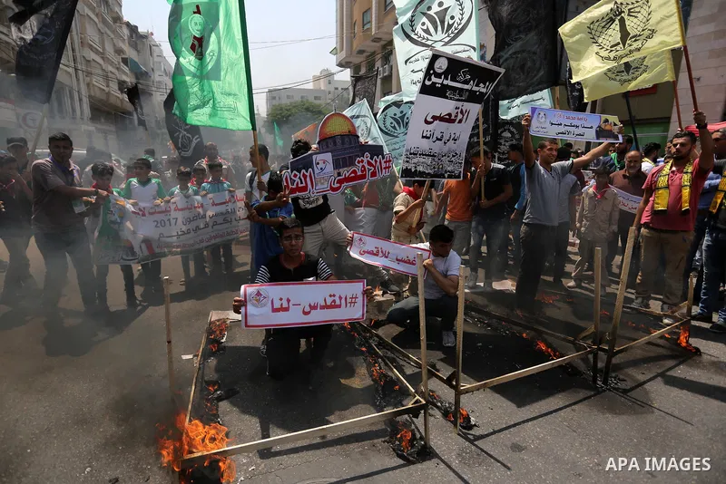Palestinian protesters burn models of metal detectors during a demonstration against Israeli security measures that were implemented at the Al-Aqsa mosque compound in Jerusalem the previous week prior to being removed af...
