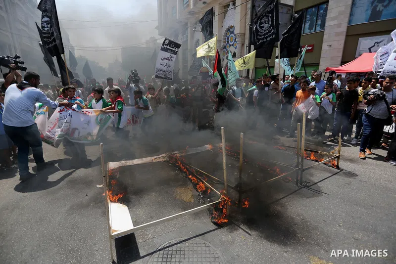 Palestinian protesters burn models of metal detectors during a demonstration against Israeli security measures that were implemented at the Al-Aqsa mosque compound in Jerusalem the previous week prior to being removed af...
