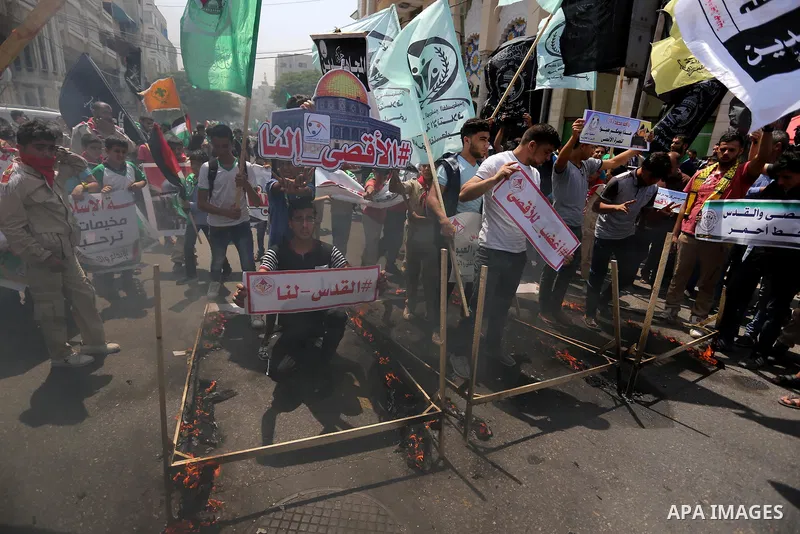 Palestinian protesters burn models of metal detectors during a demonstration against Israeli security measures that were implemented at the Al-Aqsa mosque compound in Jerusalem the previous week prior to being removed af...