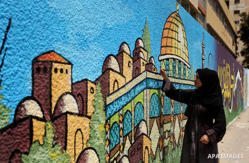 A Palestinian artist paints a mural drawing depicting the Dome of the Rock Mosque against Israeli security measures that were implemented at the Al-Aqsa mosque compound in Jerusalem the previous week prior to being remov...