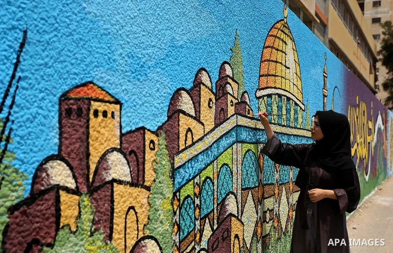 A Palestinian artist paints a mural drawing depicting the Dome of the Rock Mosque against Israeli security measures that were implemented at the Al-Aqsa mosque compound in Jerusalem the previous week prior to being remov...