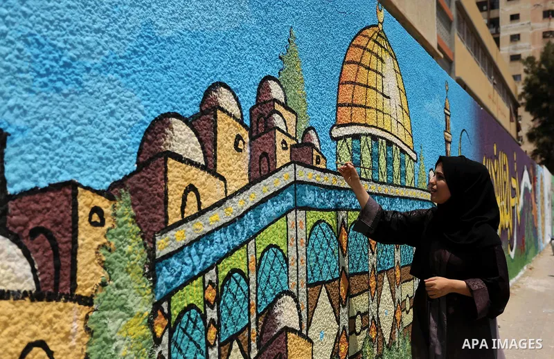 A Palestinian artist paints a mural drawing depicting the Dome of the Rock Mosque against Israeli security measures that were implemented at the Al-Aqsa mosque compound in Jerusalem the previous week prior to being remov...