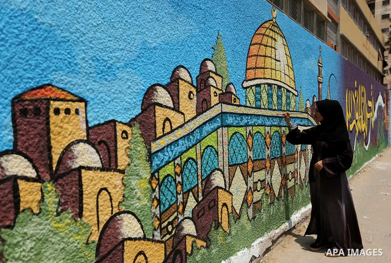 A Palestinian artist paints a mural drawing depicting the Dome of the Rock Mosque against Israeli security measures that were implemented at the Al-Aqsa mosque compound in Jerusalem the previous week prior to being remov...