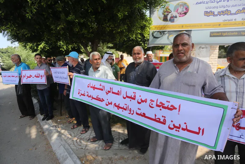 Palestinian Martyrs Families hold placards during a protest demanding their salaries in Gaza city on July 26, 2017. Photo by Mohammed Asad